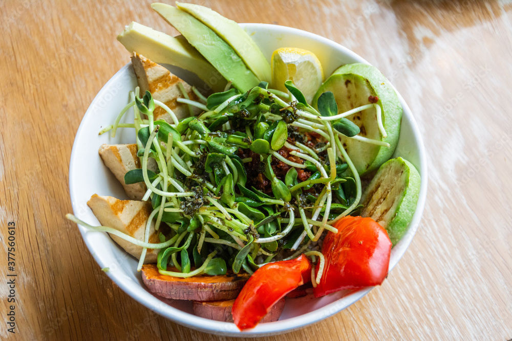 Vegan bowl with avocado, grilled tofu, zucchini and sweet potato, with greens and nuts on top Vegan bowl with avocado, grilled tofu, zucchini and sweet potato, with greens and nuts on top