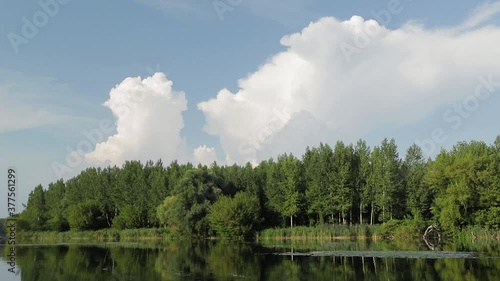 Nice clouds over old branch of Danube river, Bodiky, Slovakia. Summer sunset light. Green grass reflected in water surface.
