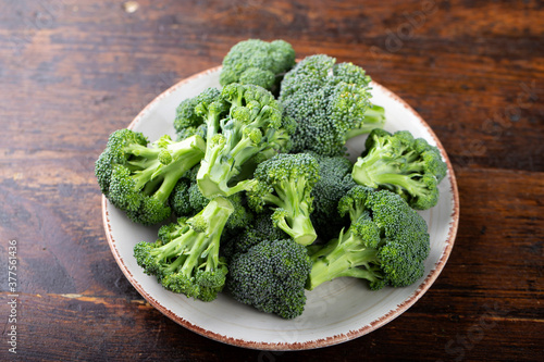 Fresh broccoli in a clay bowl on a wood background backdrop.