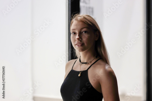 One girl in black dress stands  near white neon wall at night. Picture has dark  tones. lady outside next to the shop at night, back light, fashion concept, stylish minimalistic dress © Евгения Жигалкина