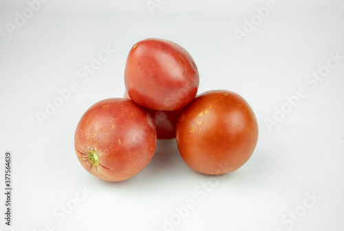 Pile of pink and red fresh tomatoes isolated on white background © Zkolra