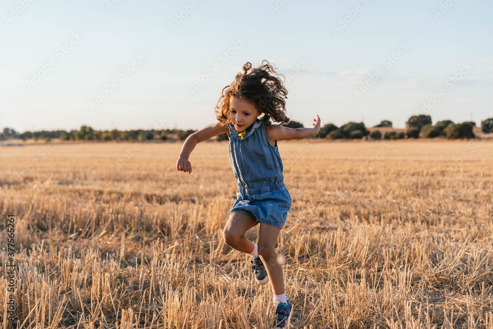 Young girl with brown hair jumping in the field during sunset Young girl with brown hair jumping in the field during sunset