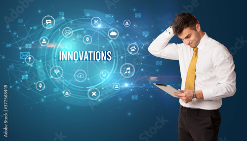 Businessman thinking in front of technology related icons and INNOVATIONS inscription, modern technology concept