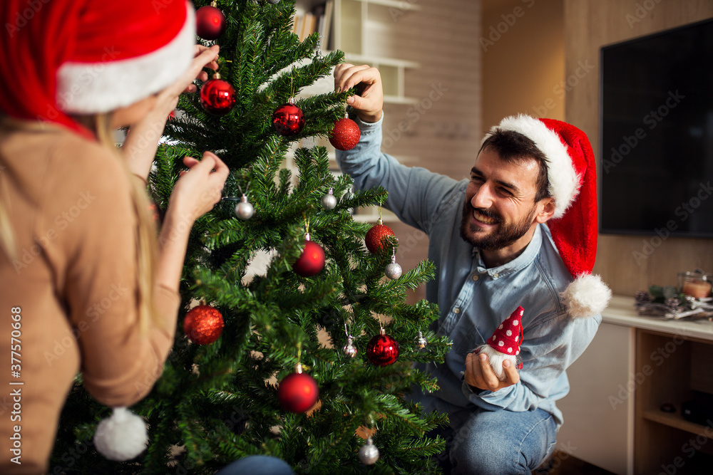Happy young couple decorating Christmas tree