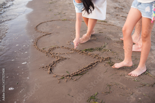 people draw hearts on wet sand with their fingers. Relax on the beach