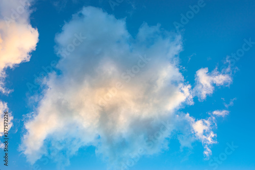 Fluffy cumulus clouds in the evening light against blue sky. Suitable as background or wallpaper.