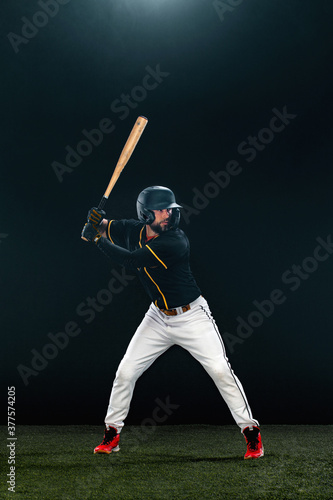 Baseball player with bat on dark background. Ballplayer portrait.