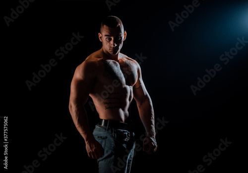 Portrait of strong man showing muscles isolated on black