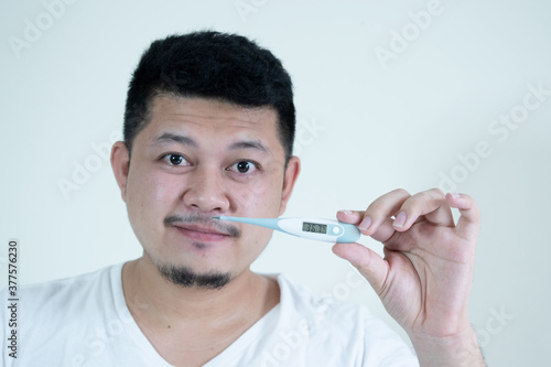 people, healthcare and fever concept - unhealthy asian man measuring oral temperature by thermometer over white background