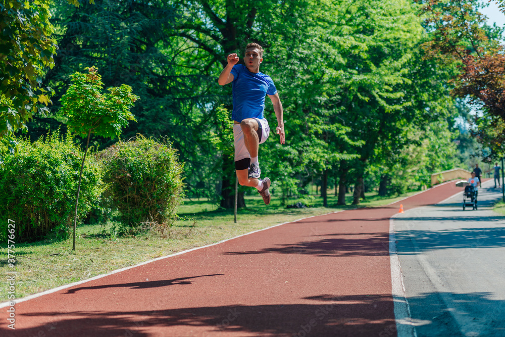 Caucasian young male runner in sportswear jumping in the park Caucasian young male runner in sportswear jumping in the park