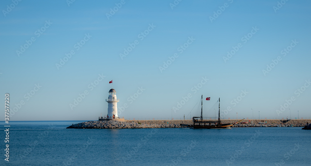 Panoramic view from the beach of the port with light house illuminated by the sunset sun