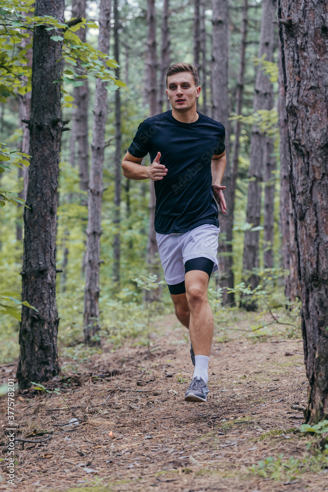 Full-length picture of an attractive male athlete running in the woods Full-length picture of an attractive male athlete running in the woods