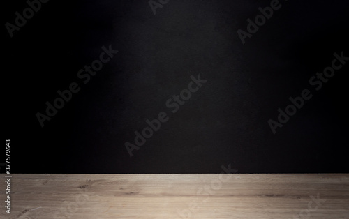 Spotlight in a dark room with a wooden background and black walls. Blank space for product or text
