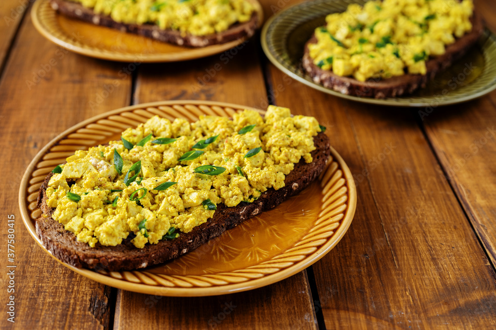Close up of a plate with bright yellow vegan egg salad sandwiches Close up of a plate with bright yellow vegan egg salad sandwiches