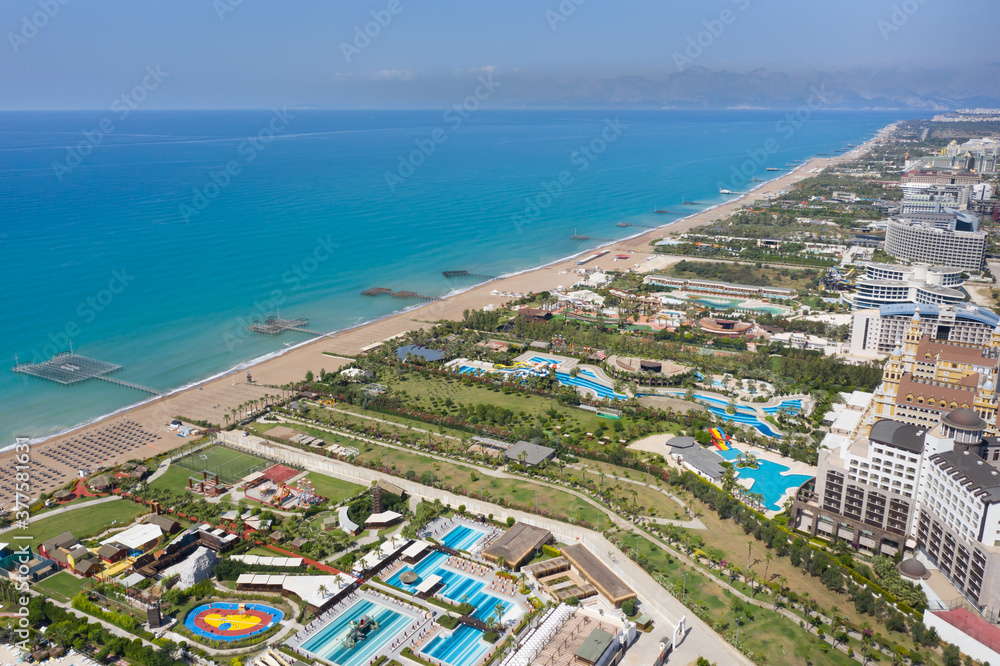 Sandy beaches of the Mediterranean. Kundu holiday complex with five star hotels. Beach, sea, water sports, parasailing, entertainment and shopping center. Aerial view with drone. Kundu, Lara -TURKEY