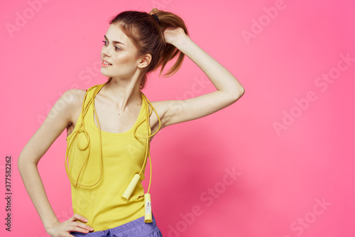 sportive woman jumping rope in hands yellow tank top pink background workout lifestyle