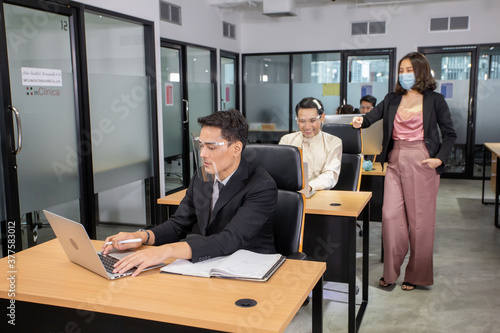 young business with face mask work plan in the office. Businessman and businesswoman using a laptop together while standing in front of office