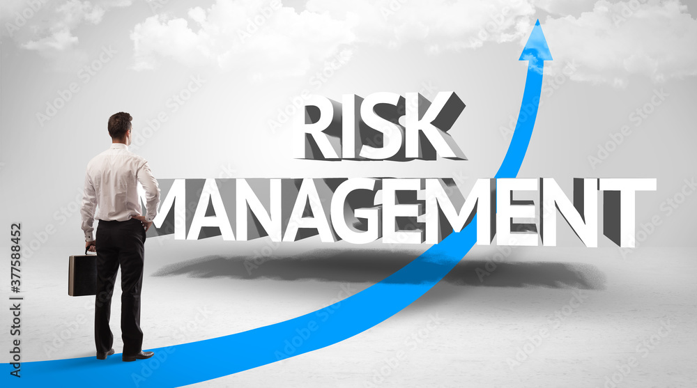 Rear view of a businessman standing in front of RISK MANAGEMENT inscription, successful business concept Rear view of a businessman standing in front of RISK MANAGEMENT inscription, successful business concept
