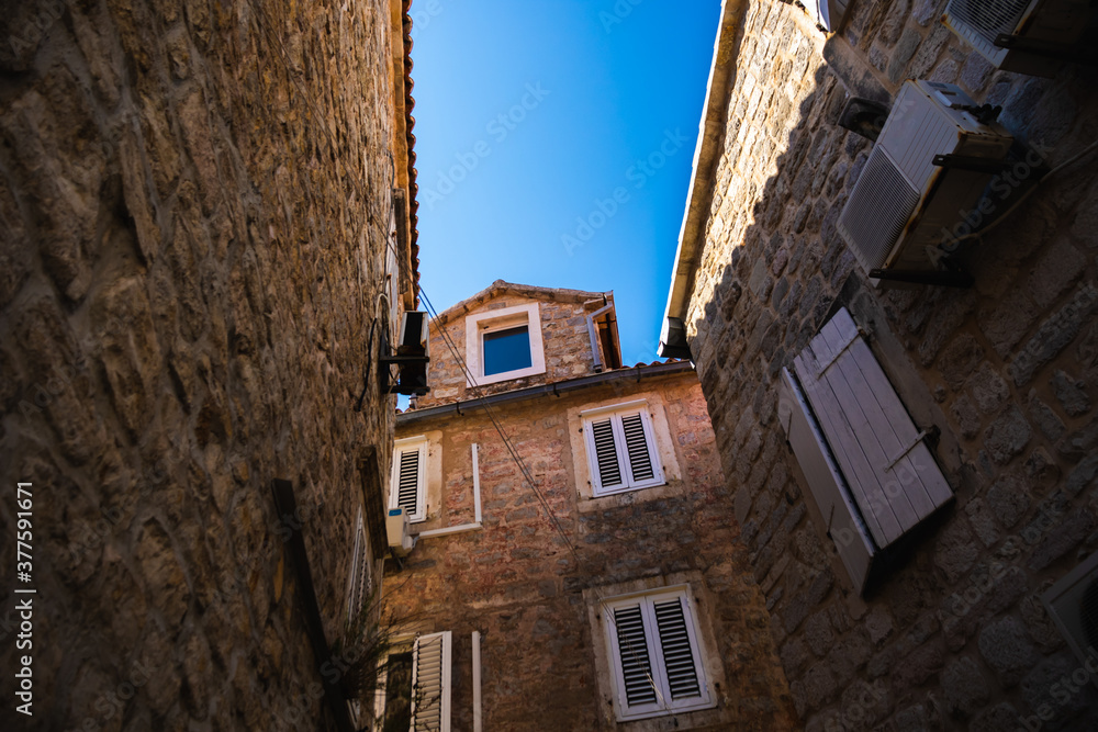 Very narrow streets of the old town with stone houses in good condition, atmospheric photo from budva