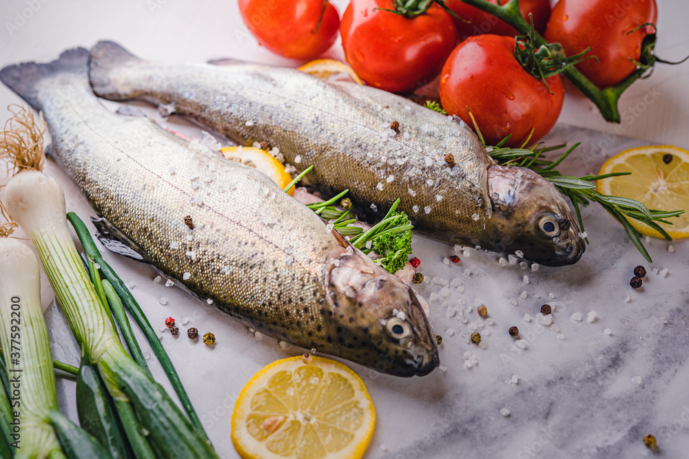 fresh rainbow fish trout on black stone background with vegetables fresh rainbow fish trout on black stone background with vegetables
