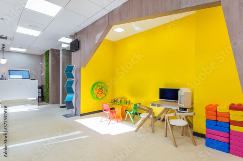 The waiting area with the play space for children. Bright yellow play space with little children's colorful furniture and toys