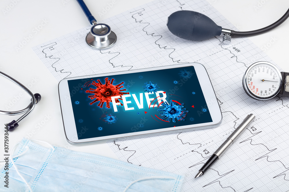 Tablet pc and doctor tools on white surface with FEVER inscription, pandemic concept Tablet pc and doctor tools on white surface with FEVER inscription, pandemic concept