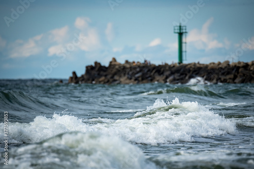 Breakwater in the Baltic Sea, beach in Darlowo. The rough sea in autumn. Foaming sea water and waves crashing against the breakwater. Stormy weather.