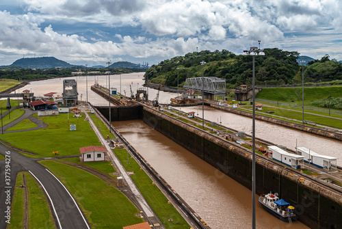 City of Knowledge, Panama - November 30, 2008: Miraflores locks. View to Pacific Ocean from the locks under cloudscape and green mountains in back. Only small boat present. © Klodien