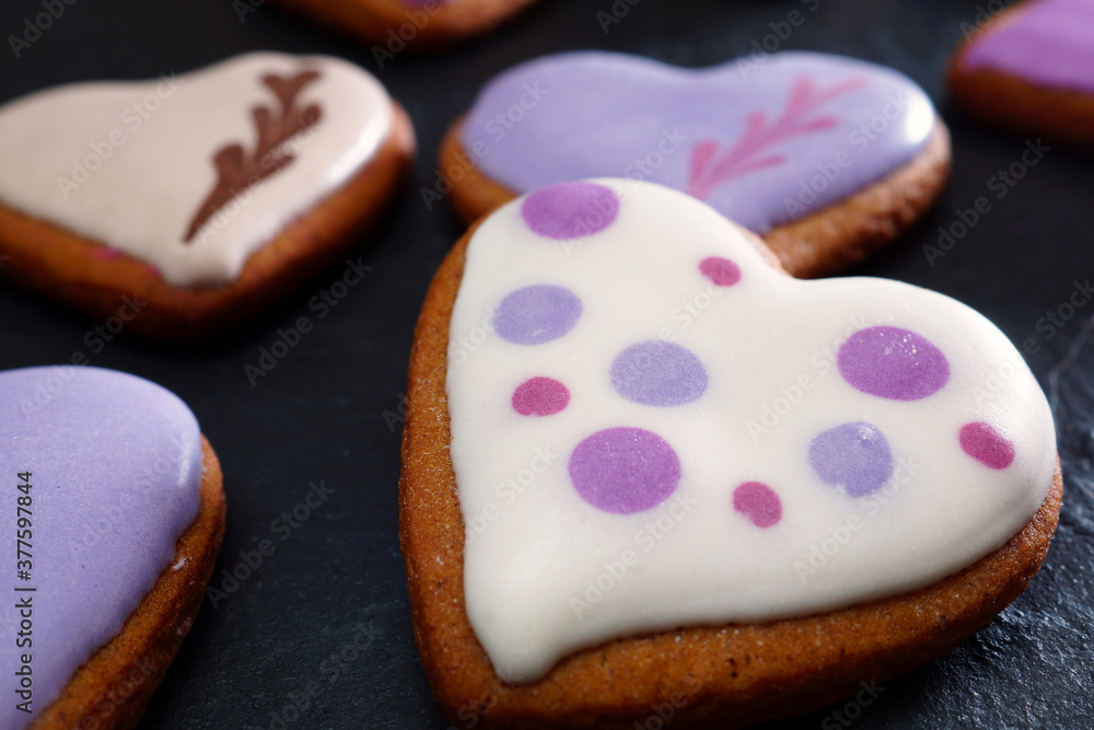 Homemade cookies in glaze. Handmade gingerbread cookies in the shape of a heart on a black table. Close-up. Shallow depth of field Homemade cookies in glaze. Handmade gingerbread cookies in the shape of a heart on a black table. Close-up. Shallow depth of field