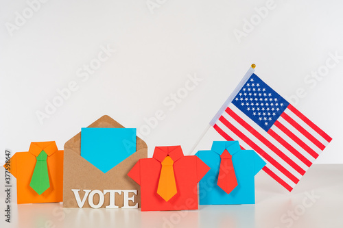 Voting in the US Presidential election. Symbolic origami men next to the word vote and the American flag. The concept of voting participation. Elections of the President in USA.