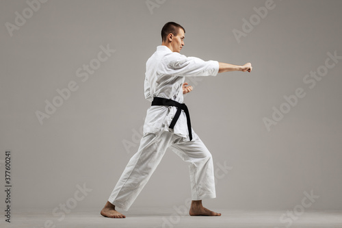 man exercising karate, against gray background