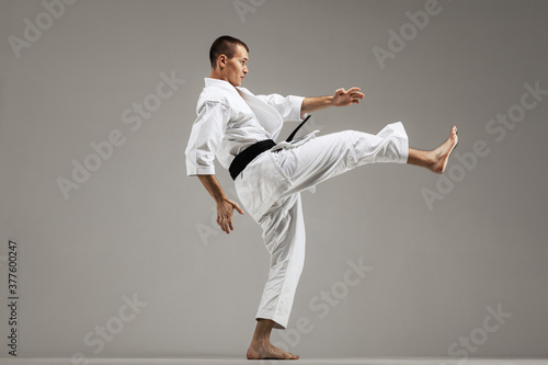 man exercising karate, against gray background