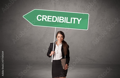 Young business person in casual holding road sign with CREDIBILITY inscription, new business direction concept photo