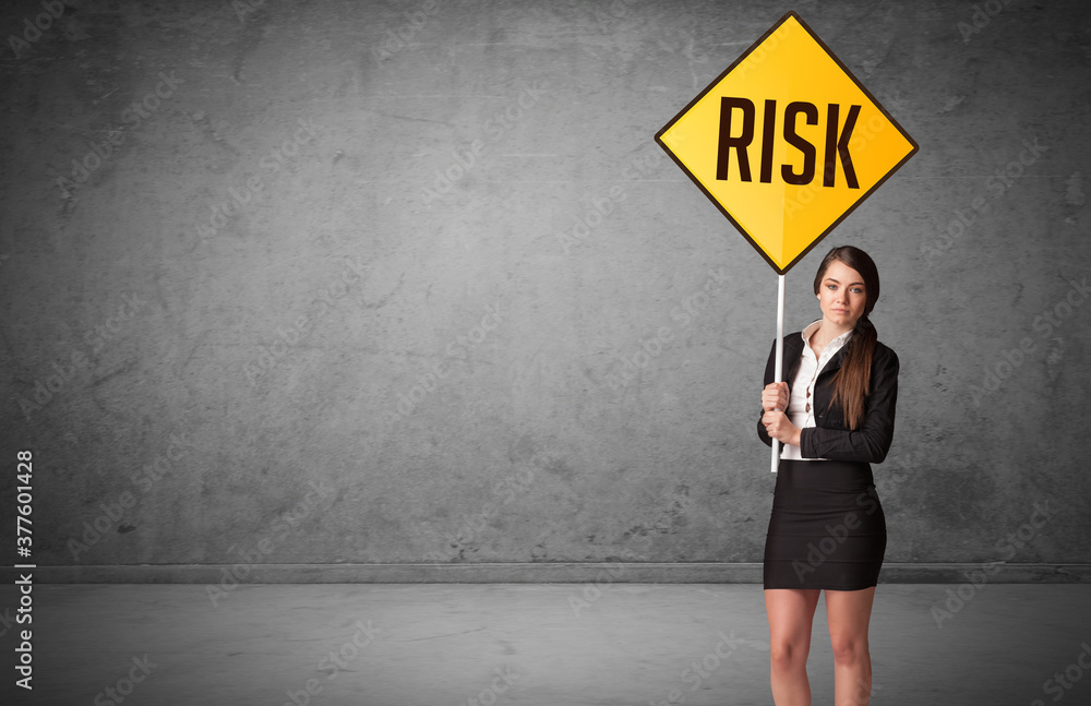 Young business person holding road sign with RISK inscription, new rules concept Young business person holding road sign with RISK inscription, new rules concept