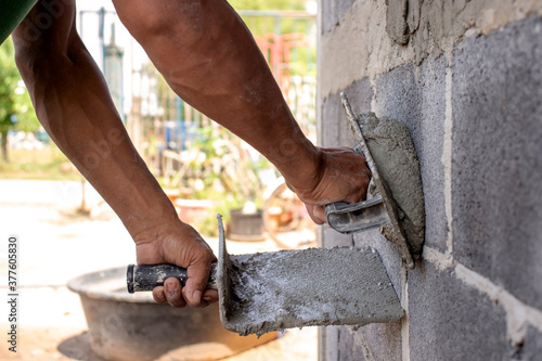 Close-up of workers using plaster trowel to plaster the walls for house construction, working ideas and residential construction.
