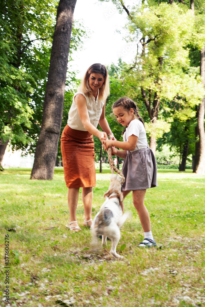 Obraz premium young pretty caucasian mother walking with little cute daughter and dog fox terrier, lifestyle people concept