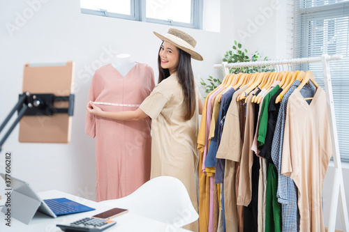 Asian woman selling vintage clothes, she is live on social media.She is measuring the shirt size.