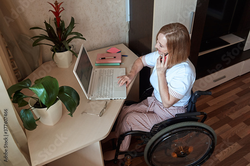 Schilderij op canvas A female freelancer, disabled in a wheelchair, works remotely from home
