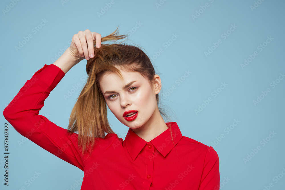 Happy girl in bright clothes on a blue background touches the hair on her head with her hands Happy girl in bright clothes on a blue background touches the hair on her head with her hands