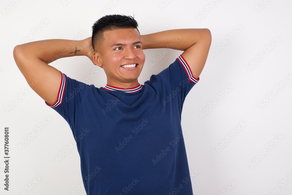 Young handsome hispanic man wearing casual t-shirt standing over white isolated background stretching arms, relaxed position. Young handsome hispanic man wearing casual t-shirt standing over white isolated background stretching arms, relaxed position.