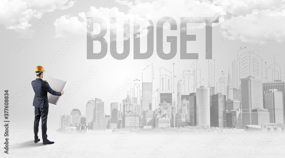 Young businessman with hard hat and BUDGET inscription, new business opportunity concept Young businessman with hard hat and BUDGET inscription, new business opportunity concept