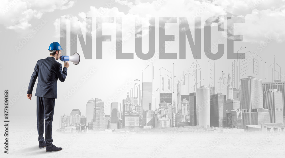 Young businessman with hard hat and INFLUENCE inscription, new business opportunity concept Young businessman with hard hat and INFLUENCE inscription, new business opportunity concept