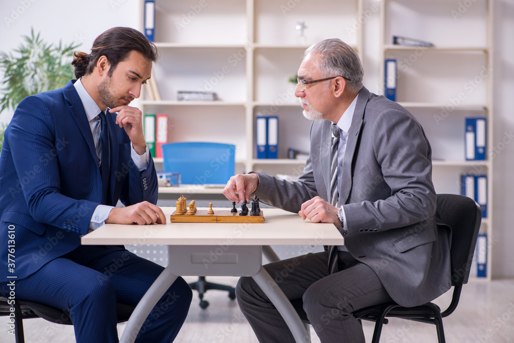 Two businessmen playing chess in the office Two businessmen playing chess in the office