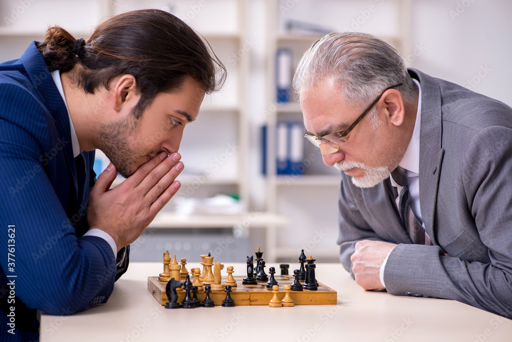 Two businessmen playing chess in the office Two businessmen playing chess in the office