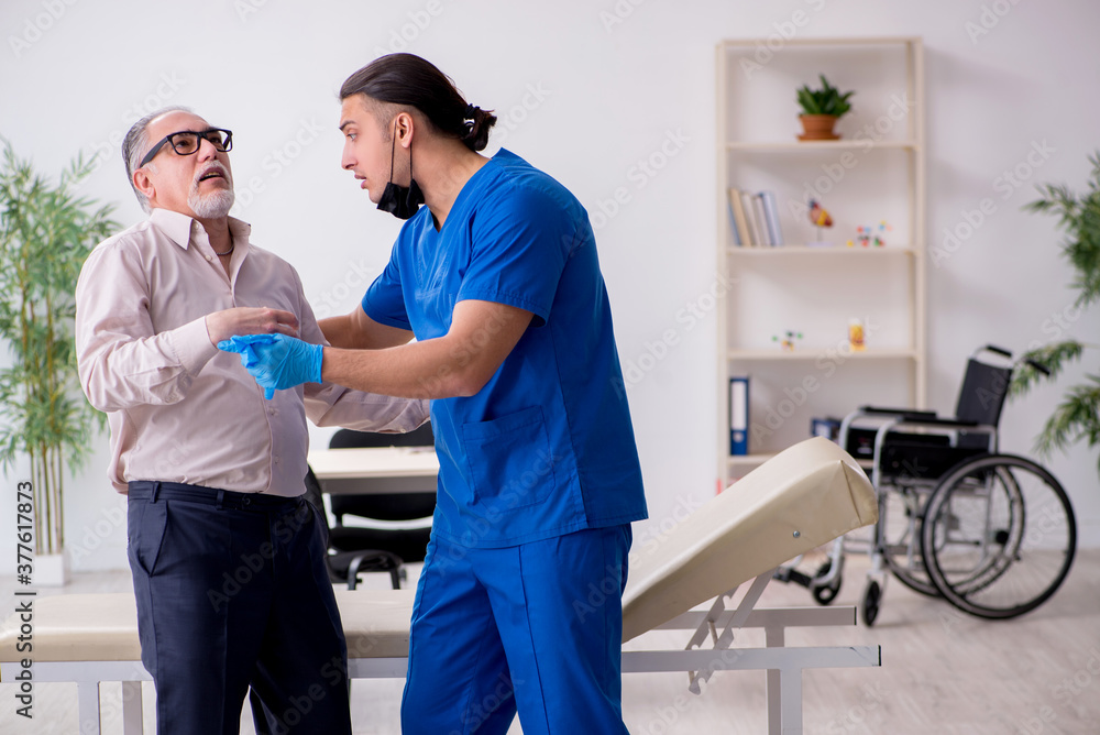 Fototapeta premium Old patient visiting young male doctor