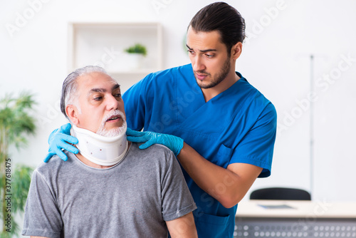 Young male doctor and old patient in first aid concept