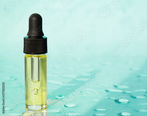 Face serum on the trendy pastel blue background with drops. Collagen, hyaluronic acid for skin care. Concept of natural cosmetics, skin care. Copy space