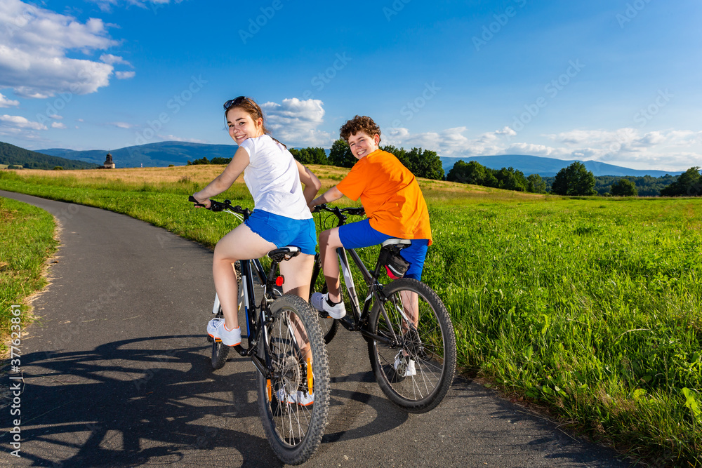 Healthy lifestyle - teenage girl and boy riding bicycles 