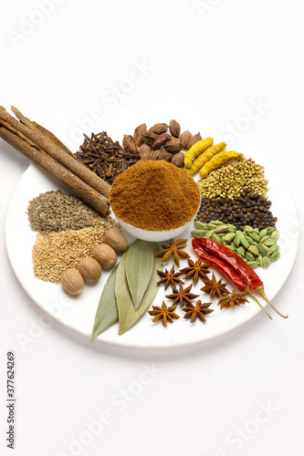 Indian spices called garam masala contents in white plate.