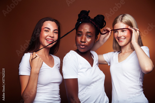 young pretty asian, caucasian, afro woman posing cheerful together on brown background, lifestyle diverse nationality people concept